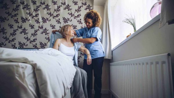 personal care assistant helping elderly woman